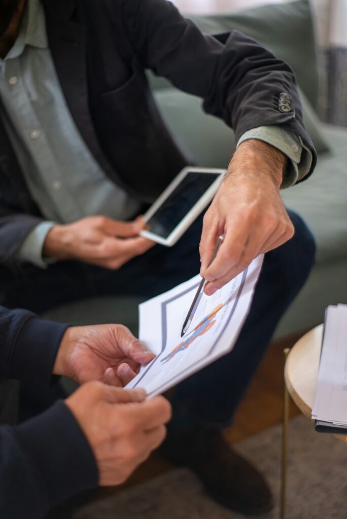 Two professionals in a business meeting discussing documents and a tablet.